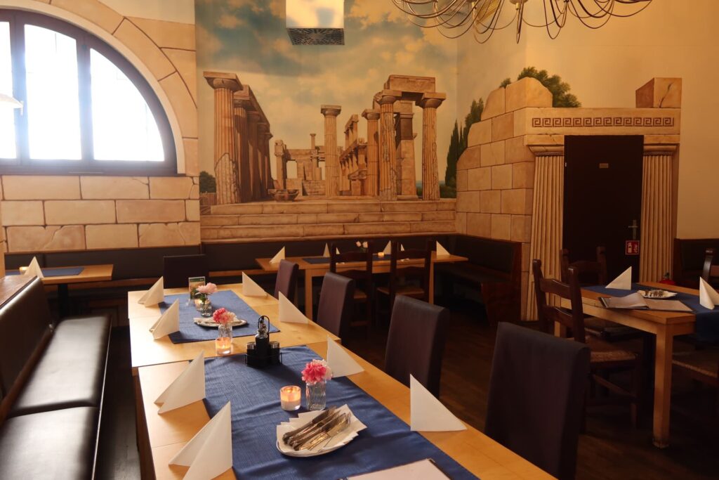 Lange Tafel mit blauen Tischläufern vor einer antiken Wandmalerei
